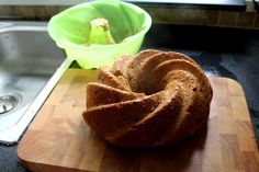 a bundt cake sitting on top of a wooden cutting board next to a green bowl