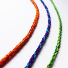 three multicolored necklaces on a white surface