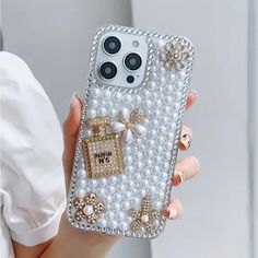 a woman holding up a cell phone case with pearls and bows on it