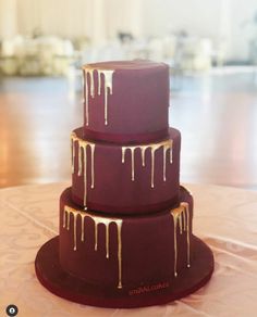 a three tiered cake with dripping icing on it sitting on a round table