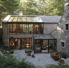 a stone house with a glass roof surrounded by greenery