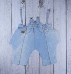 a pair of blue jean shorts hanging on a white wooden wall with the bottom cut off