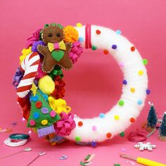 the letter o is decorated with pom poms and other colorful objects on a pink background