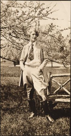 an old black and white photo of a man sitting on a bench in the grass