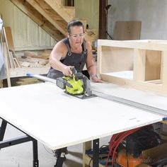 a woman using a circular saw to cut plywood planks with a table saw