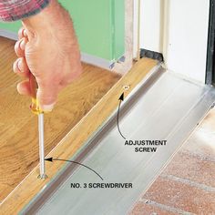 a person holding a screwdriver in front of a door with an adhesivement screw