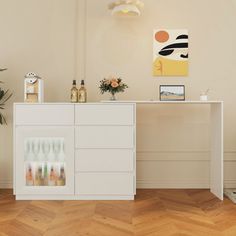 a white cabinet sitting in the middle of a room next to a potted plant