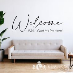 a living room with a couch and wall decal that says welcome we're glad you're here