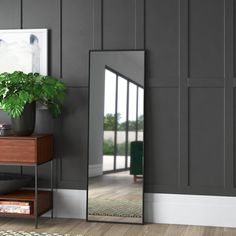 a large mirror sitting on top of a wooden table next to a potted plant