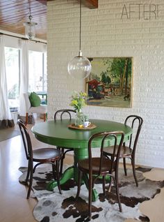 a green table with four chairs in front of a painting on the wall above it