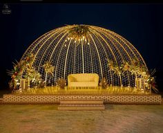 a couch sitting under a lit up dome in the middle of a field at night