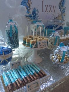 an assortment of desserts displayed on a table with blue and white decorations in the background