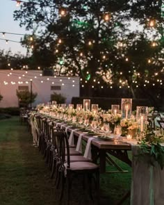 a long table is set up with candles and greenery for an outdoor dinner party