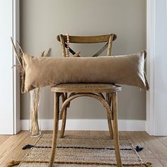 a chair with a pillow on top of it in front of a wall and door