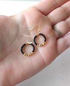 two small black and gold hoop earrings on a person's left hand, one in the foreground