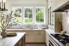 a kitchen with white cabinets and marble counter tops