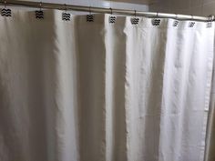 a white shower curtain with black and white chevrons on the bottom, in a bathroom