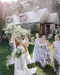 a group of women standing next to each other in front of a house