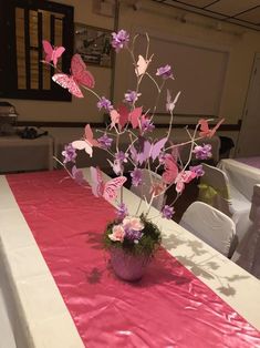 a vase filled with pink and purple flowers on top of a white table cloth covered table