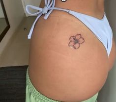 a woman's stomach with a small flower tattoo on the side of her belly