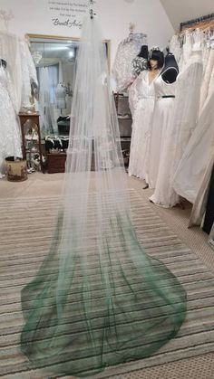 a wedding dress on display in a bridal shop with veils hanging from the ceiling