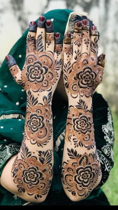 a woman's hands and feet covered in hendix with flowers on them