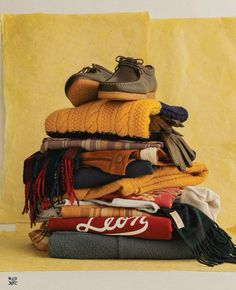 a pile of clothing and shoes sitting on top of each other in front of a yellow background