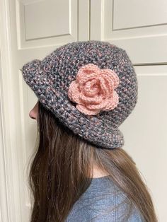 Lovely rolled brim cloche style hat that comes in charcoal/pink tweed and purple/lavender stripe. This is a great hat and has no seams with a natural roll brim to keep you warm and stylish! I use only premium yarns for all my hats and take much pride in my work. The four inch rose is made to lay flat on your hat and not flop over. Truly a great hat! Wash in a mesh bag and lay flat to dry. Ready to ship! Pink Brimmed Fedora For Winter, Pink Brimmed Cloche Hat One Size, Pink Brimmed Cloche Hat, One Size Fits Most, Handmade Cloche Hat With Curved Brim For Winter, Handmade Winter Cloche Hat, Handmade Brimmed Cloche Hat For Winter, Pink Wide Brim Cloche Hat For Winter, Pink Crochet Hat With Short Brim For Winter, Winter Crochet Hat With Curved Brim