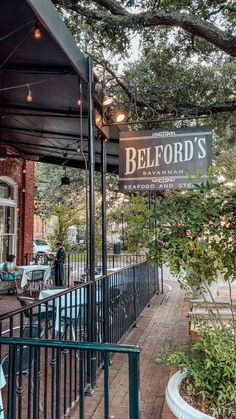 the outside of a restaurant with tables and chairs on the sidewalk next to an iron fence