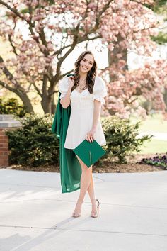 a woman in a white top and green skirt posing for the camera with her hand on her hip