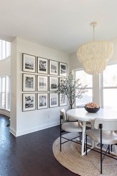 a dining room table with chairs and pictures on the wall in front of it's windows