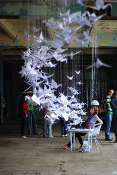 a group of people standing next to each other near a table with white paper cranes hanging from it