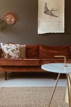 a living room with a brown couch and white table in front of the couch is decorated with birds