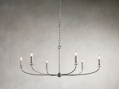 a chandelier with six candles hanging from it's center, in an empty room