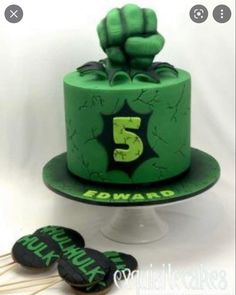 there is a green cake with the number five on it