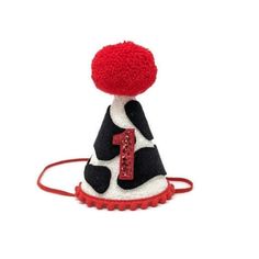 a black and white hat with a red number one on the top, sitting on a cord