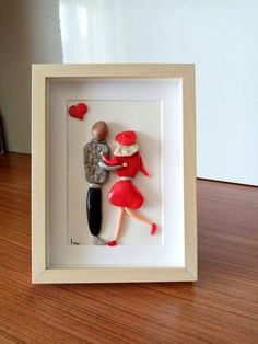 a couple is holding each other in a shadow box on a wooden table with a white frame