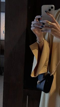 a woman taking a selfie with her cell phone while wearing a dress and jacket