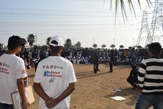 two men in white shirts standing next to each other on a field with people watching