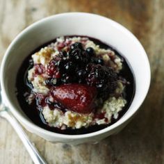 a bowl filled with oatmeal and berries on top of a wooden table