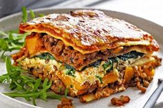 a white plate topped with lasagna and greens