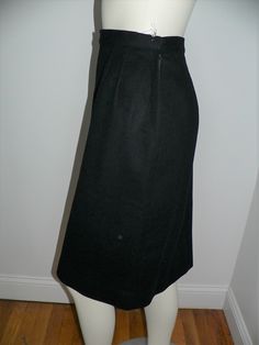 Vintage 1950's - 60's black wool skirt. It is a straight skirt with darts below the waist band on both front and back. There is a side metal zipper and snaps on the side for closure. On one side is 2 long vertical strips of black satin 3 - 4 inches wide. Inside these strips are a series of black satin diamonds starting with one at top then 2 and 3 at the bottom. There is a small back kick pleat. Inside the back set is lined in a black satiny fabric. No labels. Shown on form unpinned and loose at Office Wool Skirt In Black, Fitted Black Wool Skirt, Black Fitted Wool Skirt, Fitted Wool Full Skirt, Formal Black Wool Skirt, Formal Fitted Skirt With Box Pleats, Black Wool Lined Skirt, Formal Fitted Retro Skirt, Fitted Black Skirt With Box Pleat