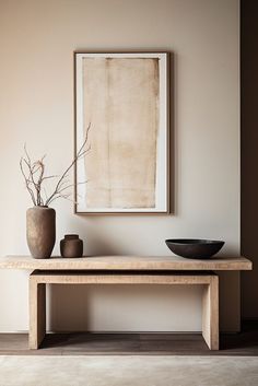 a table with two vases and a painting on the wall