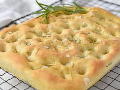 a square pastry sitting on top of a cooling rack with rosemary sprigs in it