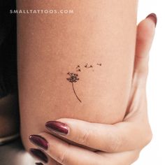 a woman's arm with a small dandelion tattoo on her left side