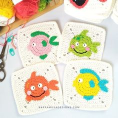 four crocheted coasters with fish on them next to scissors and yarn balls