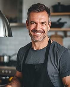 a man in an apron is smiling at the camera