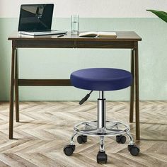 a blue stool sits in front of a desk with a laptop on it and a plant next to it