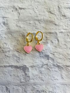 These cute and dainty gold-plated huggie earrings feature mini pink heart charms! Trendy Huggie Heart Earrings For Valentine's Day, Pink Heart Charm Huggie Jewelry, Pink Huggie Jewelry With Heart Charm, Pink Heart Charm Hoop Earrings For Valentine's Day, Pink Hoop Earrings With Heart Charm For Valentine's Day, Pink Huggie Heart Earrings, Trendy Huggie Heart Earrings With Heart Charm, Trendy Huggie Earrings For Valentine's Day, Pink Dainty Huggie Earrings