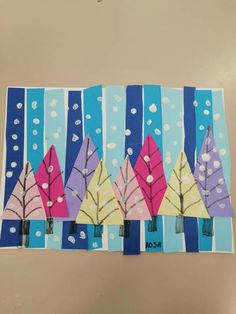 an art project made out of paper with trees and snowflakes on the background